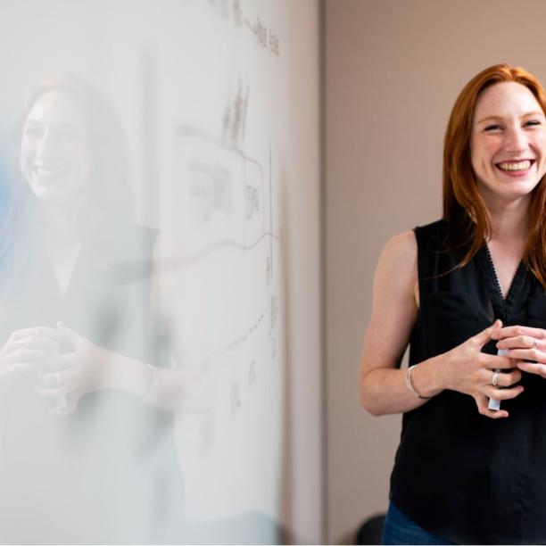 Teacher smiling stood in front of a whiteboard